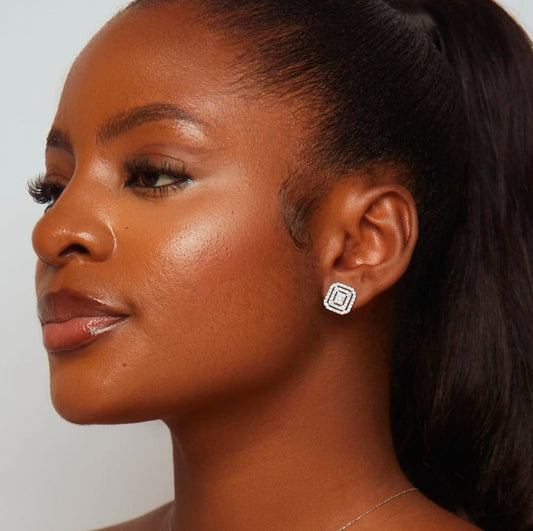 A close-up image of a person wearing a diamond stud earring, with the focus on the earring's sparkle and the soft lighting on the skin.
