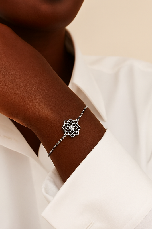 Silver bracelet with a geometric design on a wrist against a white shirt background