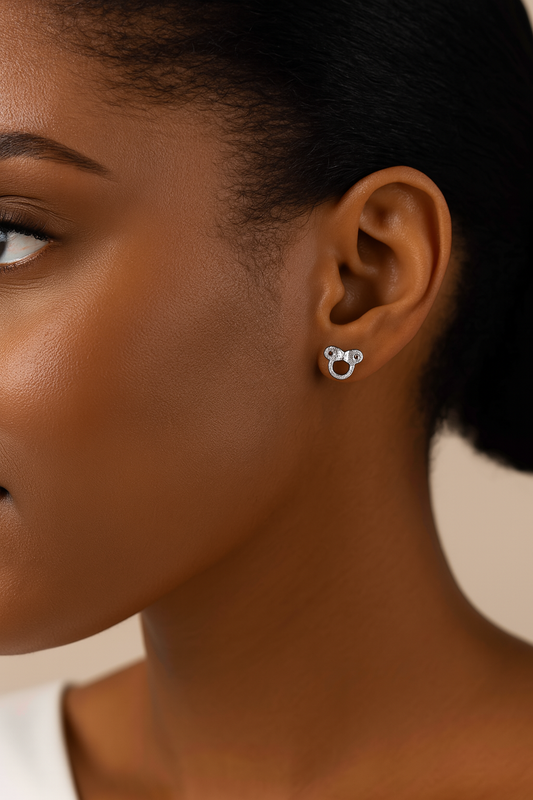 Close-up of a person wearing silver hoop earrings with a neutral background