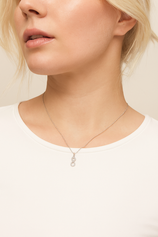 Close-up of a person wearing a delicate necklace with a small pendant on a plain background