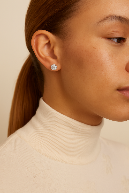 Close-up of a person wearing a silver earring with a beige background