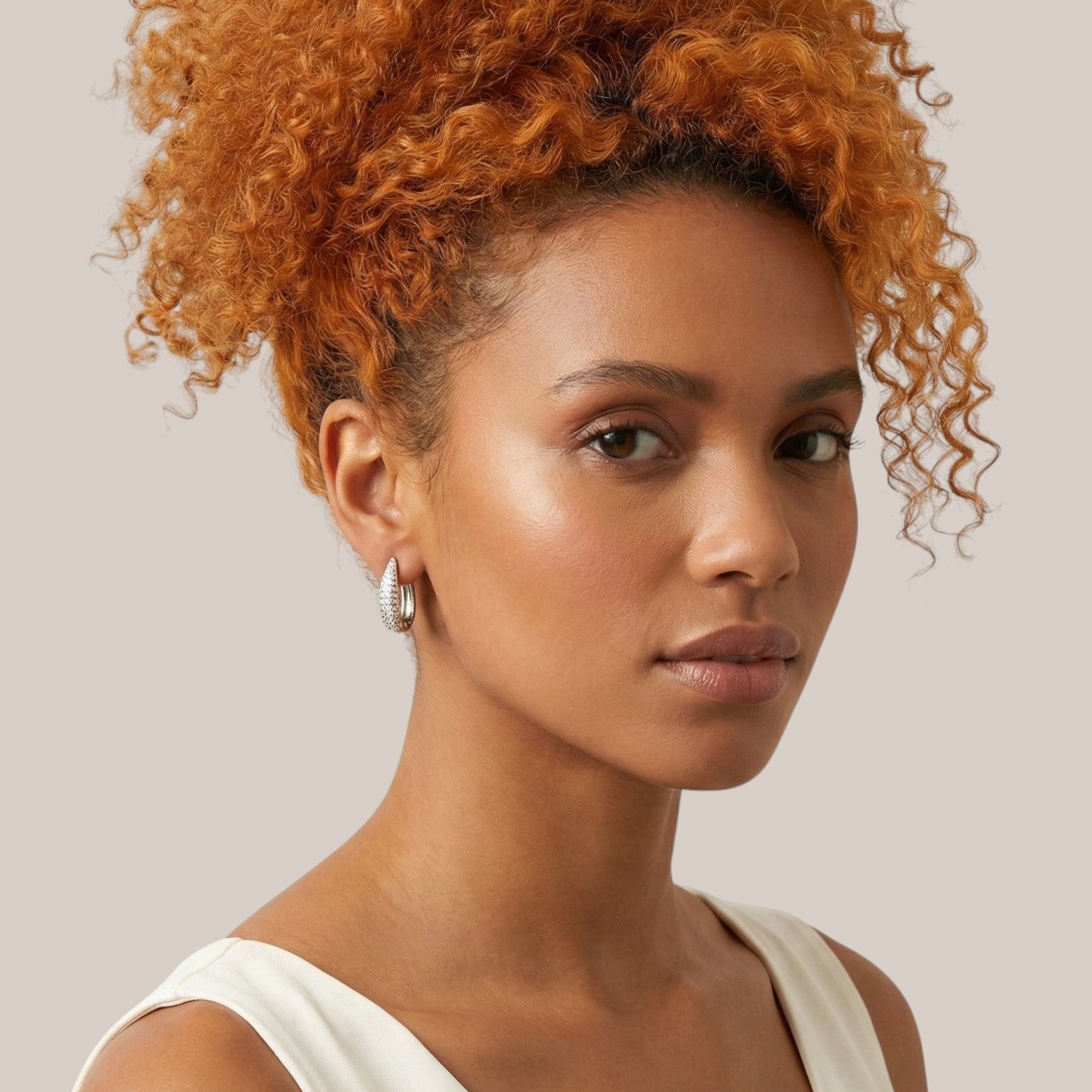 Woman with orange hair wearing a white top against a neutral background