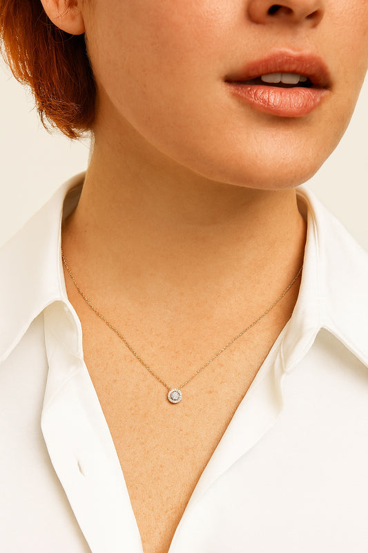 Close-up of a person wearing a delicate necklace with a small pendant on a plain background