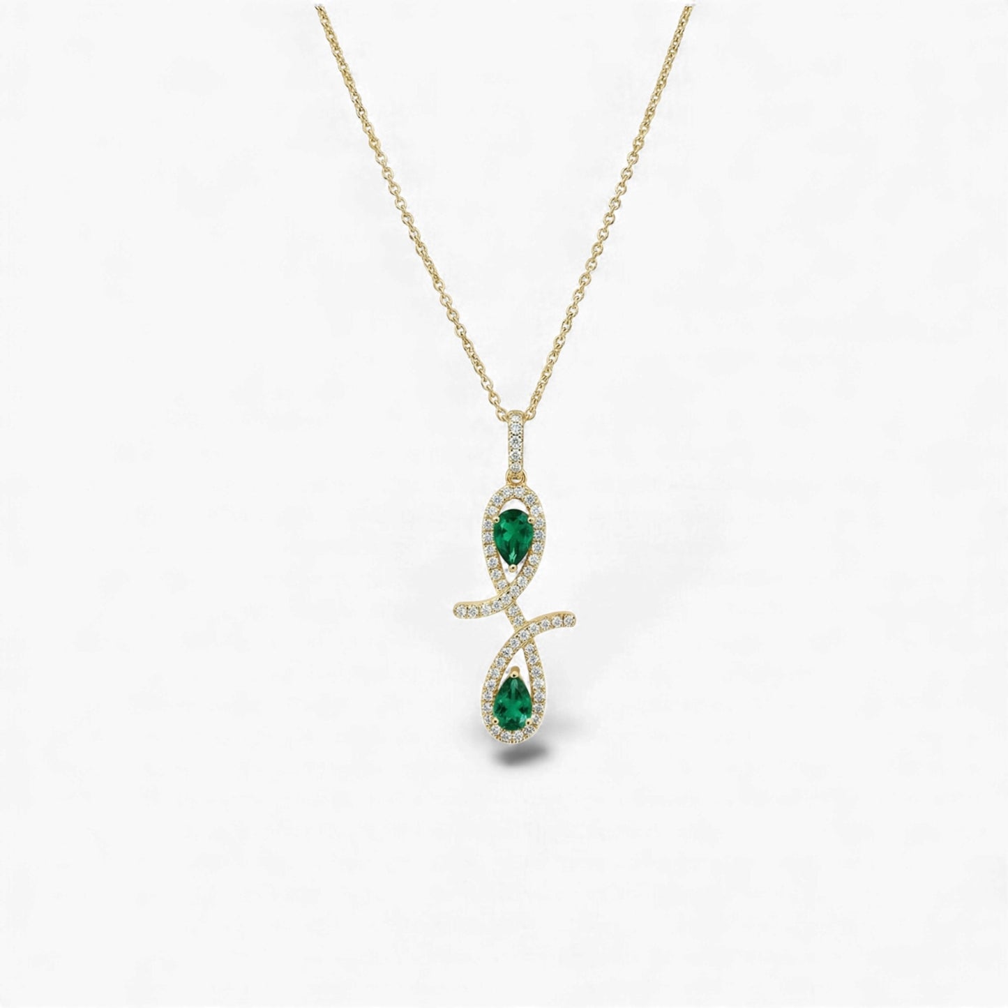 Gold necklace with a pendant featuring green gemstones on a white background