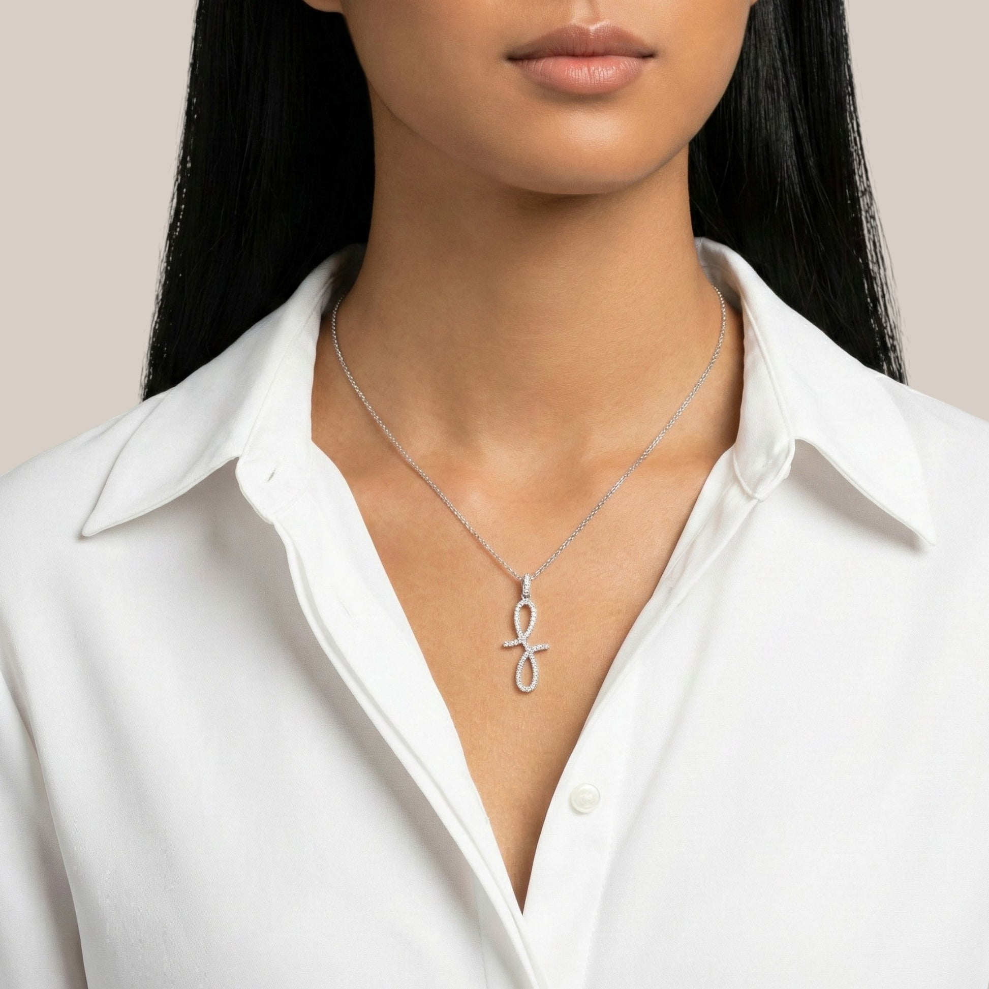 Person wearing a silver necklace with a unique pendant against a neutral background