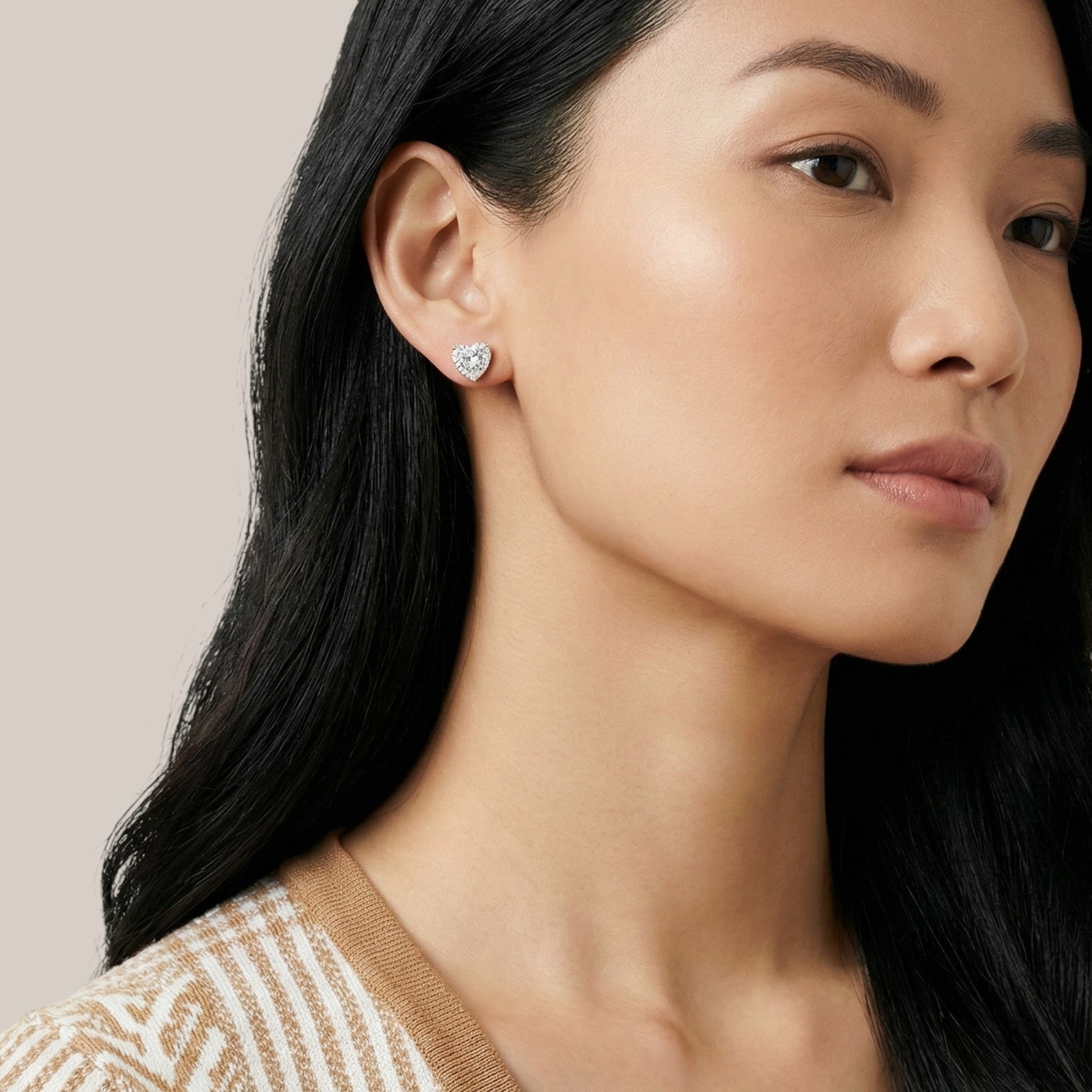Close-up of a woman wearing diamond earrings with a neutral background
