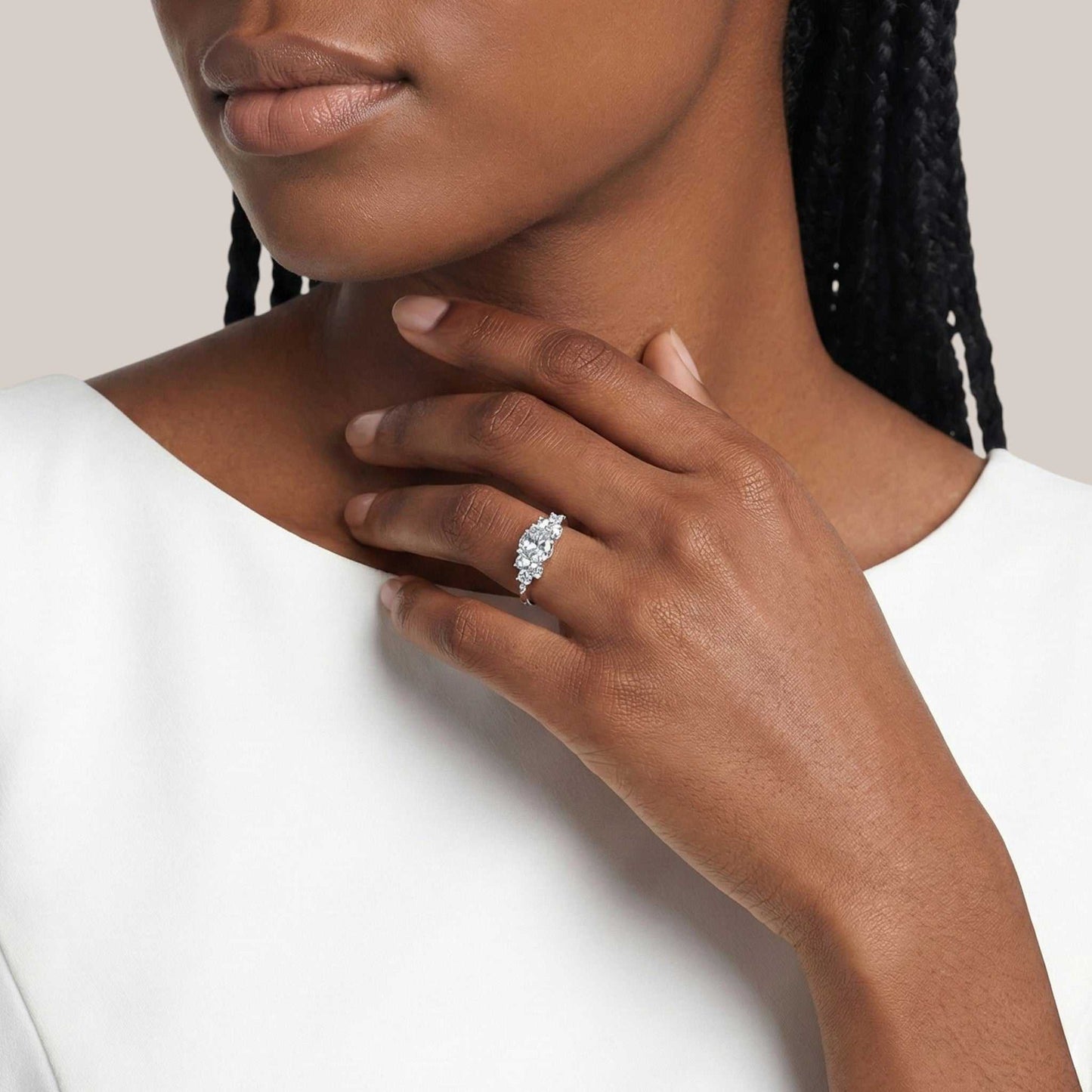 Close-up of a hand wearing a diamond ring on a neutral background
