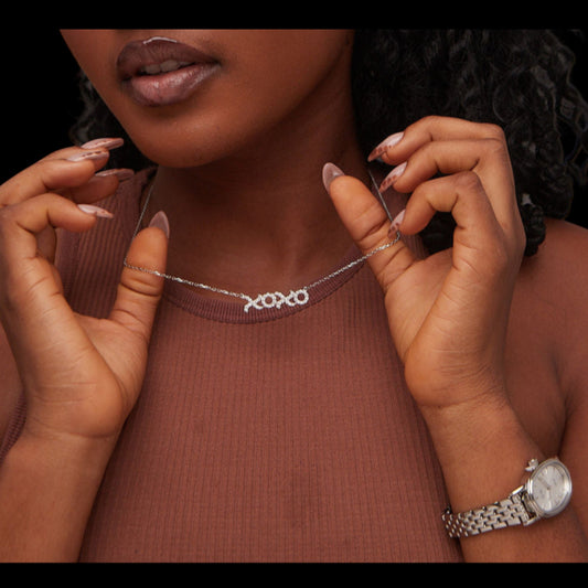 Woman wearing a silver necklace and watch, with a close-up on the jewelry.