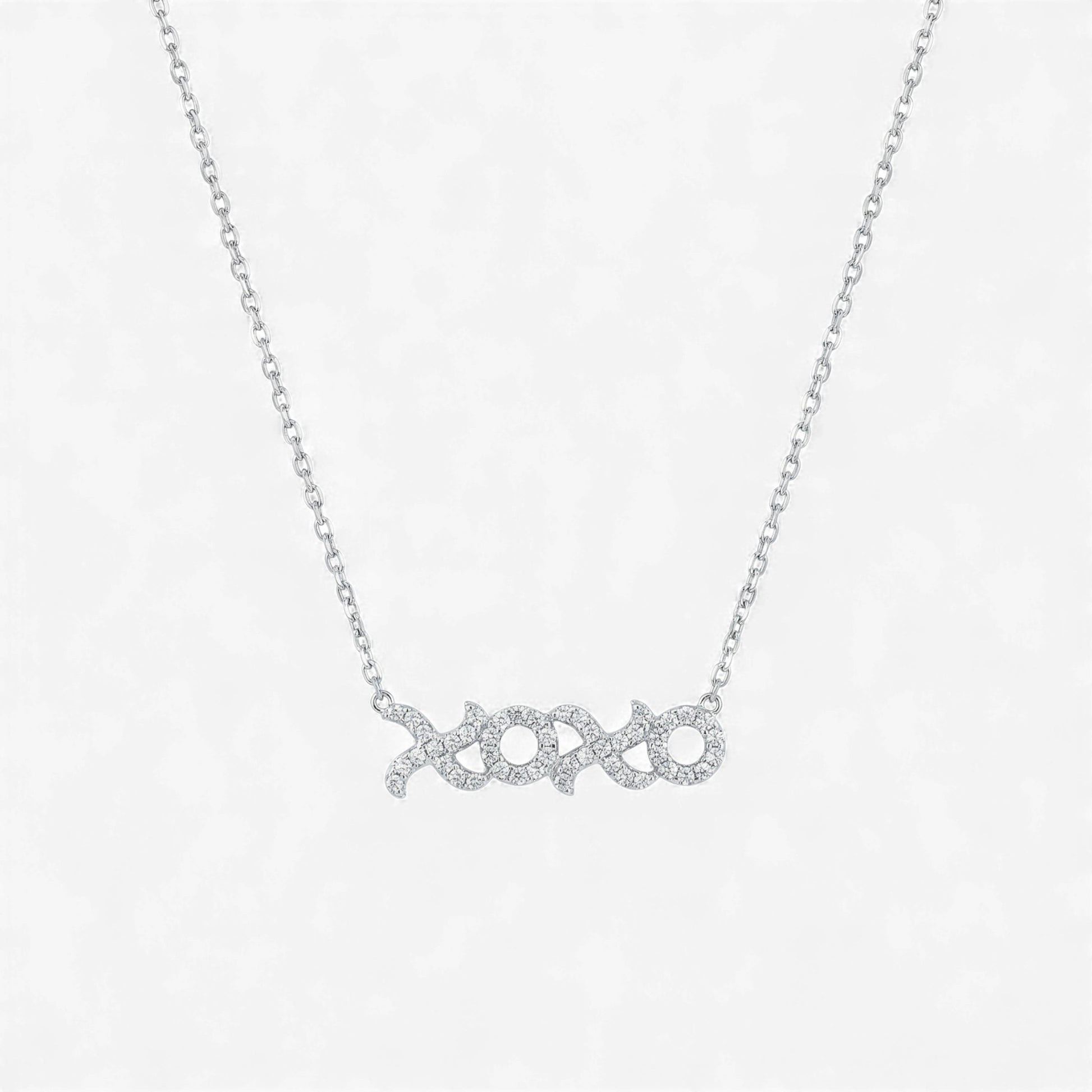 Silver necklace with 'xoxo' pendant on a light gray background