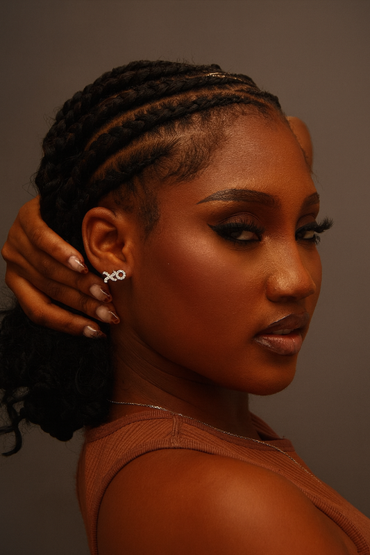 Woman with braided hair wearing a brown top against a neutral background