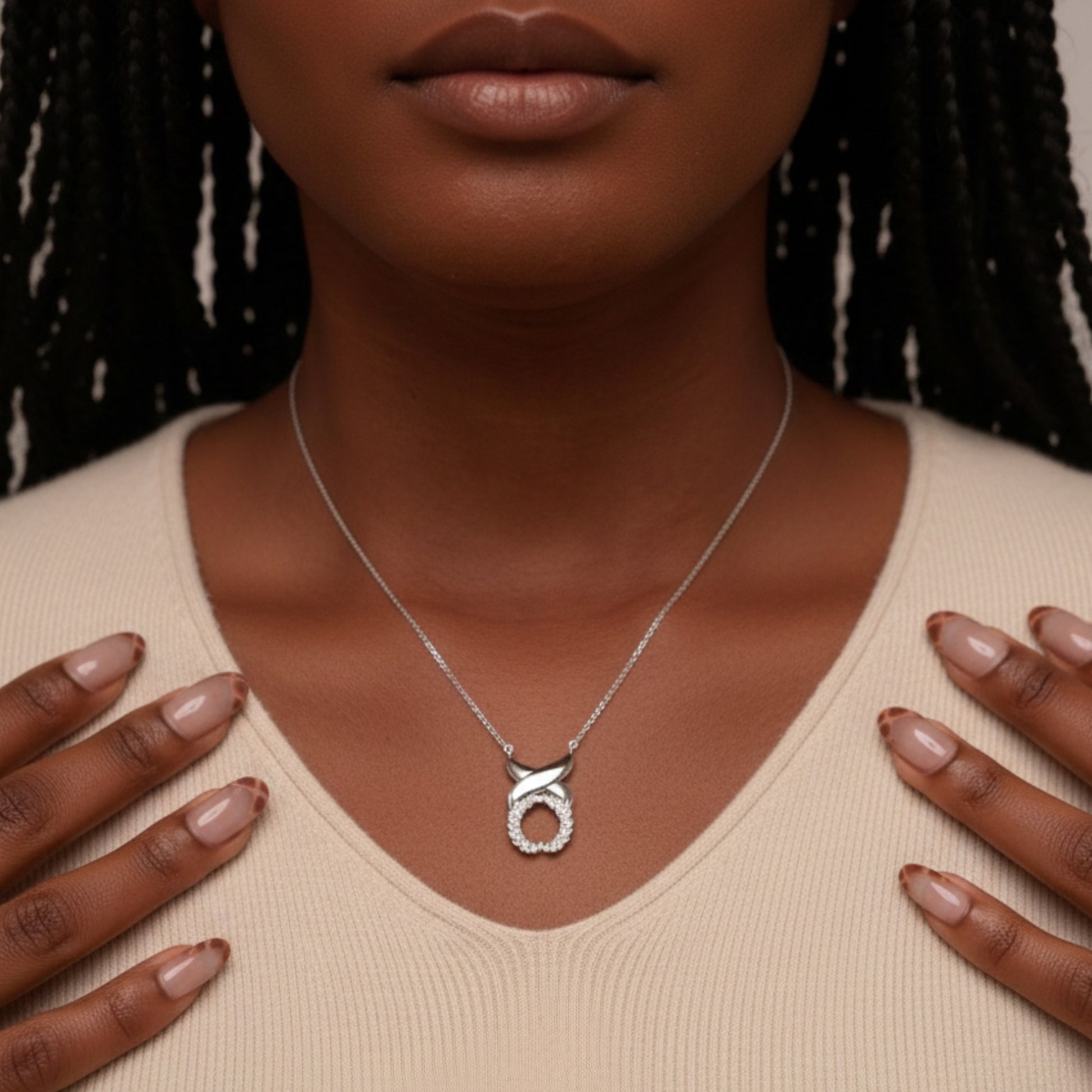Silver necklace with a pendant worn by a person against a neutral background