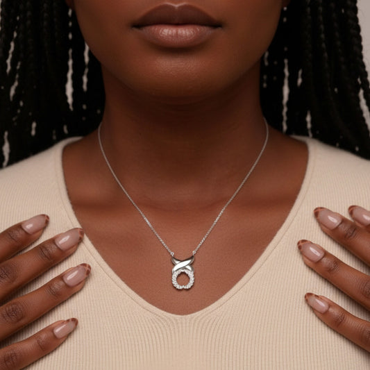 Silver necklace with a pendant worn by a person against a neutral background