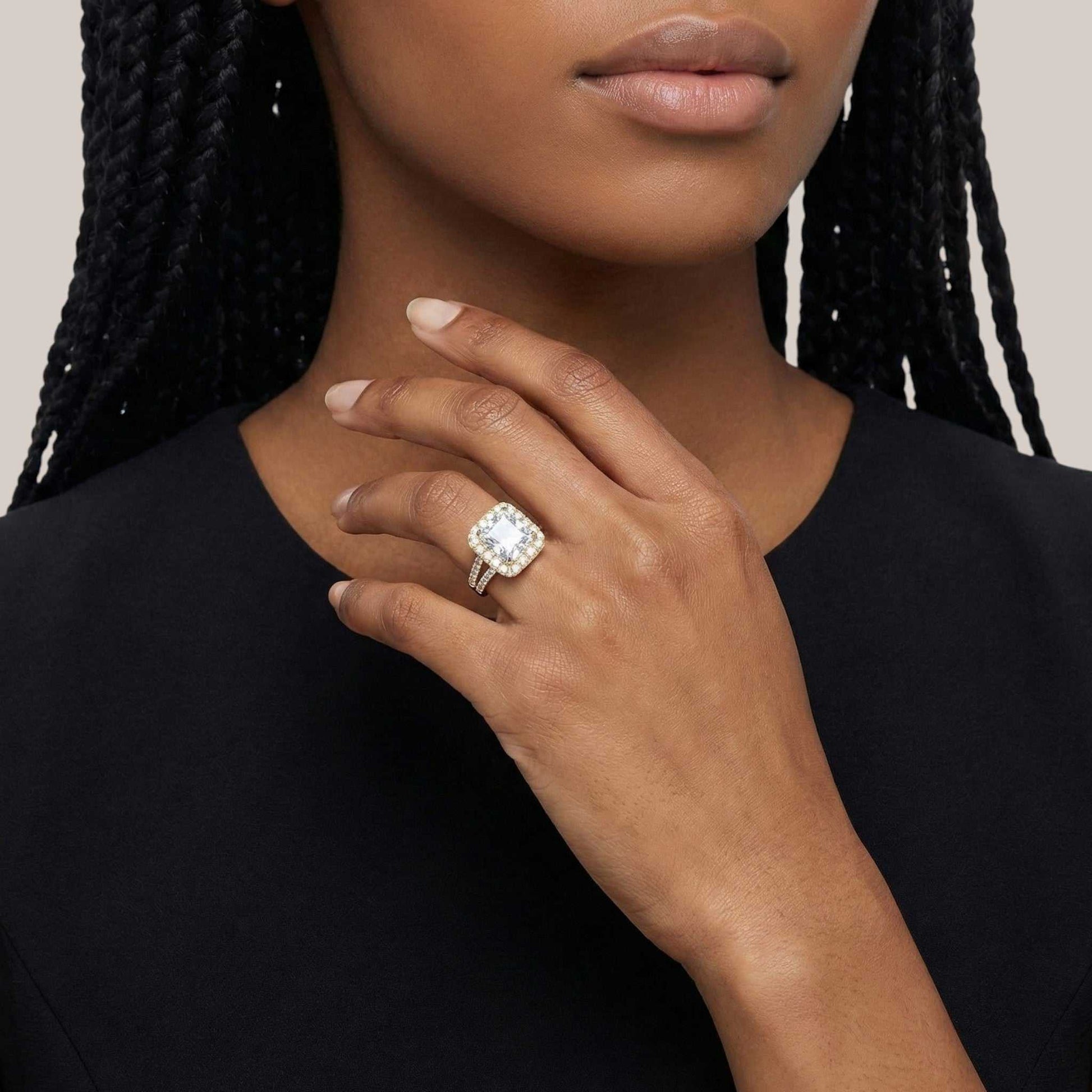 Close-up of a hand wearing a diamond ring with a neutral background