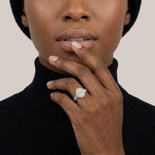 Close-up of a person wearing a diamond ring on a plain background