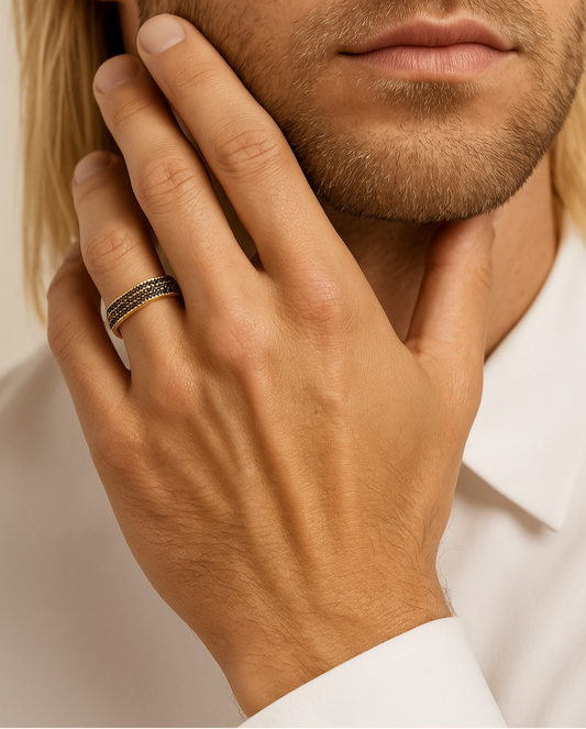 Close-up of a man's hand with a ring on his finger, touching his face.