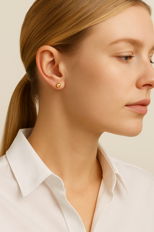 Close-up of a woman wearing gold earrings with a plain background