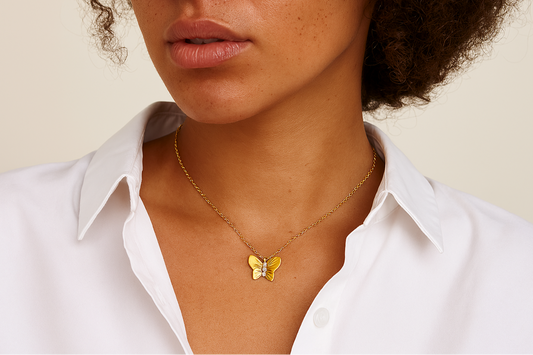Woman wearing a gold butterfly necklace against a neutral background