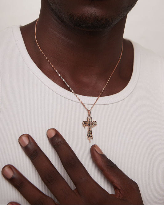 Man wearing a gold cross necklace on a plain background