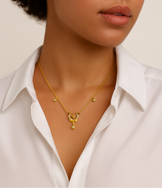 Woman wearing a gold necklace with a white shirt on a neutral background