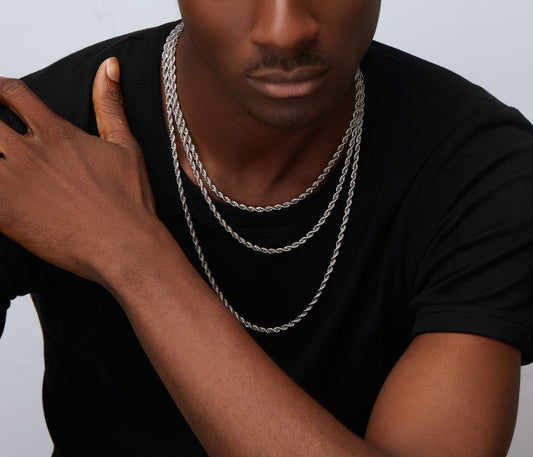 A person wearing a black shirt is showcasing a sterling silver box chain necklace.